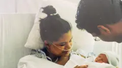 With a pillow behind her head and lots of wires and tubes attached to her, Samina Ali lies in a hospital bed, looking down at her baby son, Ishmael, in her arms, while her mother and younger brother, on either side of her, watch closely.