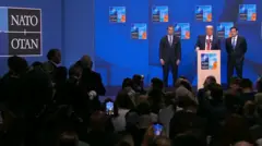 El secretario de Defensa de Estados Unidos, Pete Hegseth, Donald Trump y el secretario de Estado, Marco Rubio, se encuentran en un podio mientras Trump habla.