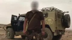 Un agent de Wagner devant un véhicule blindé.
