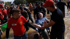 Grupo carrega homem ferido em carrinho de pedreiro em meio a enchente