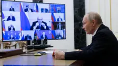 Путин сидит за столом перед экраном с множеством окон видеосвязи