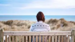 Persona sentada sola frente al mar