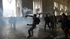Un manifestamte lanza algo en medio de enfrentamientos con la policía antidisturbios en la estación de tren Milano Centrale, en Milán, el 22 de septiembre de 2025.