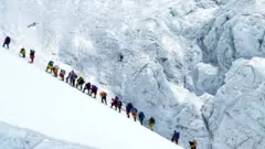 Climbers walk in a long queue as they head to summit Mount Everest in the Solukhumbu distric
