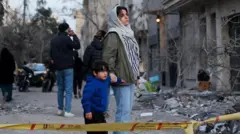 یک زن و پسرش در میان ویرانه‌های بازمانده از حملات هوایی 