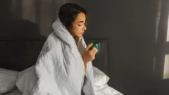 침대에서 차를 마시는 여성의 모습