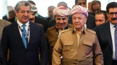 Mesrur ve Mesud Barzani yürüyor. Etraflarında yetkililer var.