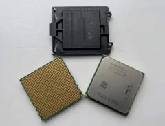 Las tres partes de un chip de AMD se ven puestas sobre un fondo blanco. Son tres piezas, una plástica de color negro, una verde con circuitos dorados, y uno verde con una pieza sólida de aluminio.