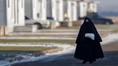 Mulher membro do grupo Lev Tahor, caminhando com sua vestimenta tradicional pelas ruas de Ontário, no Canadá