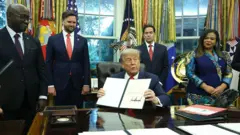 Perezida w'Amerika Donald Trump afashe ibaruwa mu ntoki yashyizeho umukono, ashimira impande zombi ubwo yahuraga na Minisitiri w'ububanyi n'amahanga w'u Rwanda Olivier Nduhungirehe na Minisitiri w'ububanyi n'amahanga wa DRC Thérèse Kayikwamba, nyuma yo gushyira umukono ku masezerano y'amahoro. Aha bari kumwe na Visi Perezida w'Amerika JD Vance (wa kabiri ibumoso) na Minisitiri w'ububanyi n'amahanga Marco Rubio. Ifoto yafotorewe mu biro bya perezida w'Amerika (White House), ku wa gatanu, ku itariki ya 27 Kamena (6) mu mwaka wa 2025. 