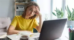 امرأة تنظر بقلق إلى جهاز الكمبيوتر المحمول الخاص بها