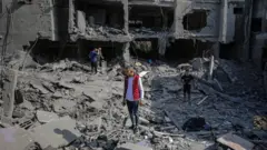 أربعة فلسطينيين يقفون فوق مبان مدمرة في غزة بحثاً عن جثث وناجين.