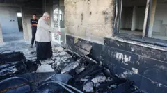 A view of the destruction on the exterior walls of Al-Rahmah Mosque as a Palestinian man points at damage