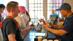 Pessoa fazendo pagamento com o telefone celular em uma cafeteria