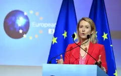 صورة لمسؤولة السياسة الخارجية في الاتحاد الأوربي كايا كالاس وهي تتحدث في مؤتمر صحفي وخلفها علم كبير للتكتل الأوربي. 