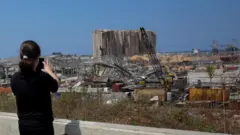 A woman takes a picture of the damaged Beirut port after the explosion
