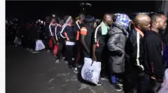 Aworan awọn eeyan ti wọn tò lọ́wọọ̀wọ́ pẹlu ọra lọwọ