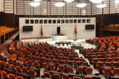 TBMM Genel Kuruldaki boş sıralar ve kırmızı vekil koltuklarını gösteren tepeden bir Meclis görünümü. 