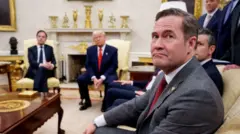 Mike Waltz pictured looking into the camera in the foreground during a meeting in the Oval Office - Mark Rutte is visible sitting next to Donald Trump, with Pete Hegseth also visible next to Waltz