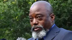 Photo en gros plan de Joseph Kabila, crâne rasé, portant une barbe grise et un costume bleu. 