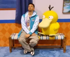 Homem sentado ao lado de um pokemón