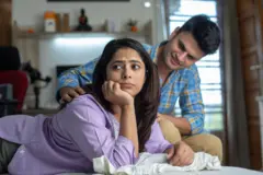 A young husband trying to convince upset wife lying on comfortable bed at home