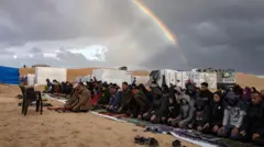يظهر قوس قزح بينما يؤدي النازحون الفلسطينيون، صلاة عيد الفطر بجوار خيامهم التي أقيمت بالقرب من الحدود المصرية، في مخيم رفح بجنوب قطاع غزة