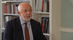 بوين مرتدياً بدلة رسمية تميل إلى اللون الرمادي الغامق وقميص سكني وربطة عنق حمراء.