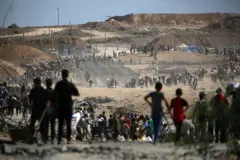 فلسطينيون يحملون حقائب يعودون من نقطة توزيع طعام تديرها مؤسسة غزة الإنسانية، المدعومة من الولايات المتحدة وإسرائيل، بالقرب من معبر نتساريم وسط قطاع غزة، في 5 أكتوبر/تشرين الأول 2025.
