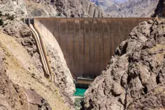 Reservatório com baixo nível de água pode ser visto entre as rochas, com a parede da represa Amir Kabir sobre a extensão de água