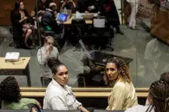 Luyara e Anielle sentadassuperbet siteplateia da sala do tribunal, olhando para trás com olhar sério