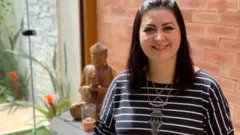 Basile sorrindo em ambiente interno iluminado