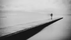 Una mujer camina hacia el final de un muelle