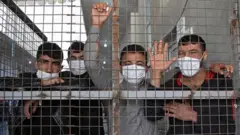 Syrians who returned from Turkey standing at a quarantine facility in the countryside of the town of Jisr al-Shughur, west of the mostly rebel-held Syrian province of Idlib, 27 April 2020