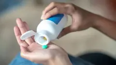 Таблеткани идишидан қўлига олаётган аёл