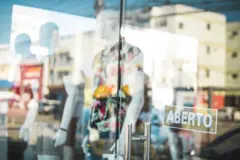 Vitrine de loja com manequins e placa de 'aberto'