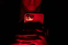 Jovem usando celular no escuro