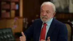 Lula sentado em uma cadeira durante entrevista para a BBC. Ele usa um terno azul e uma gravata vermelha