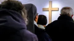 Fiéis rezando diante de uma cruz