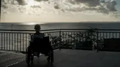 Un anciano en una silla de ruedas mira al mar