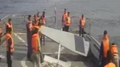 تصاویر تلویزیون ایران نشان می دهد بیش از ۱۲ پرسنل نیروی دریایی ایران در حال هل دادن دو شناور بدون سرنشین آمریکا از عرشه شناور خود به داخل دریا هستند