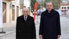 Bahçeli ve Erdoğan yan yana bir sokakta duruyor ve poz veriyor