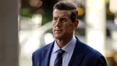 A front-on shot of Roberts-Smith looking pensively away from camera while wearing a suit and tie with strong background bokeh, as he walks along a street while arriving at the Federal Court in Sydney in May 2025.