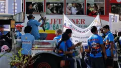 Пассажирский автобус проезжает мимо митингующих с транспарантами