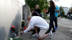 銃撃のあった学校前に献花する人々