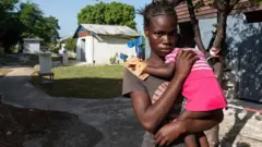 Una mujer carga a una niña