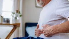 رجل يضغط على بطنه على السرير