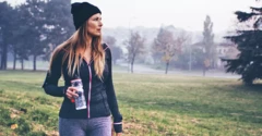 Woman holding coffee walking outside