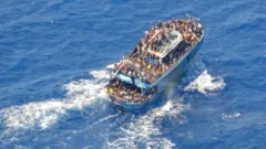صورة غير مؤرخة نشرها خفر السواحل اليونانية تظهر مهاجرين على متن قارب أثناء عملية إنقاذ، قبل انقلاب قاربهم في عرض البحر