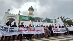 Aksi bendera putih di depan pintu gerbang Masjid Raya Baiturrahman, Banda Aceh, Kamis (18/12).